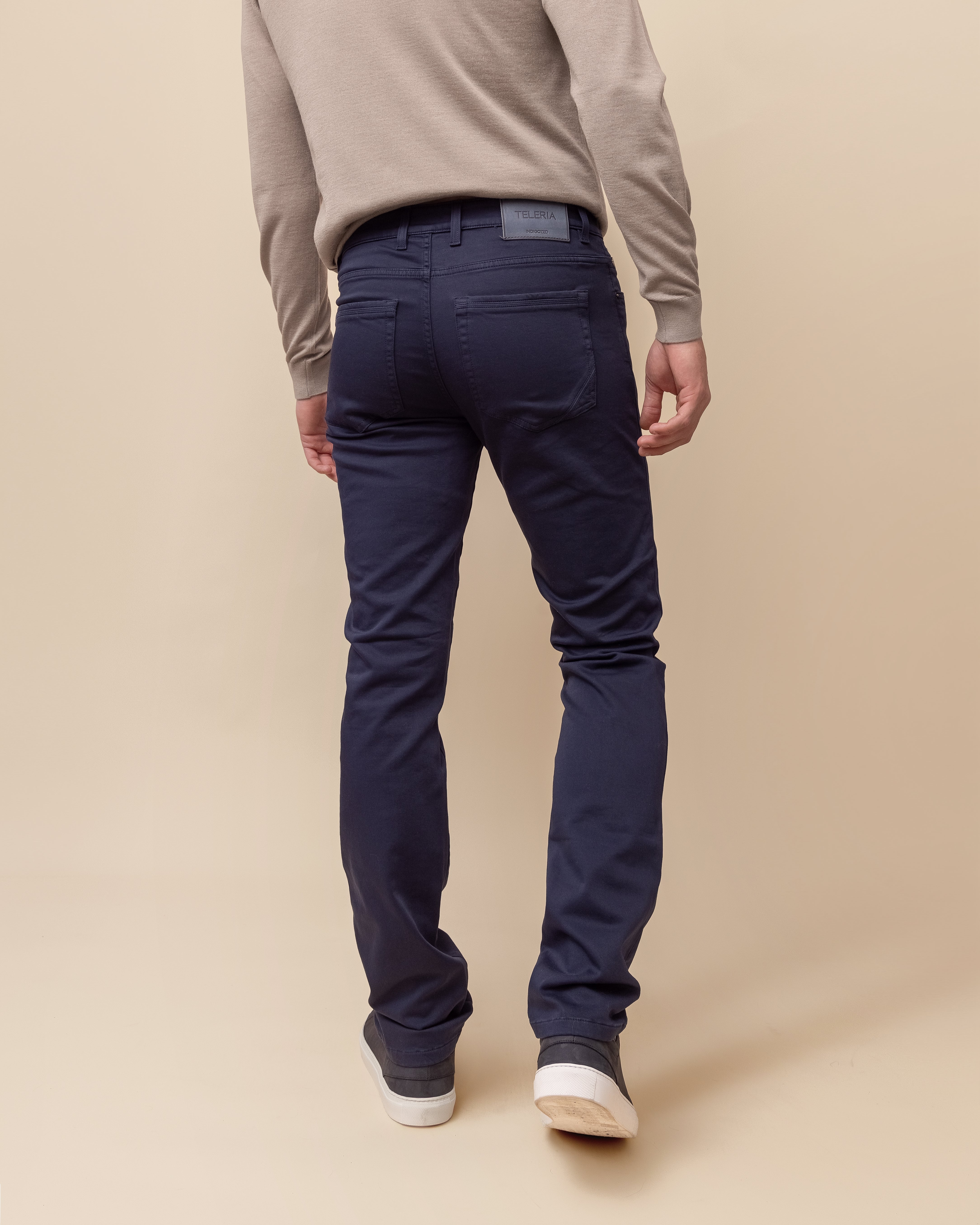 Person wearing navy pants and a beige sweater on a beige background