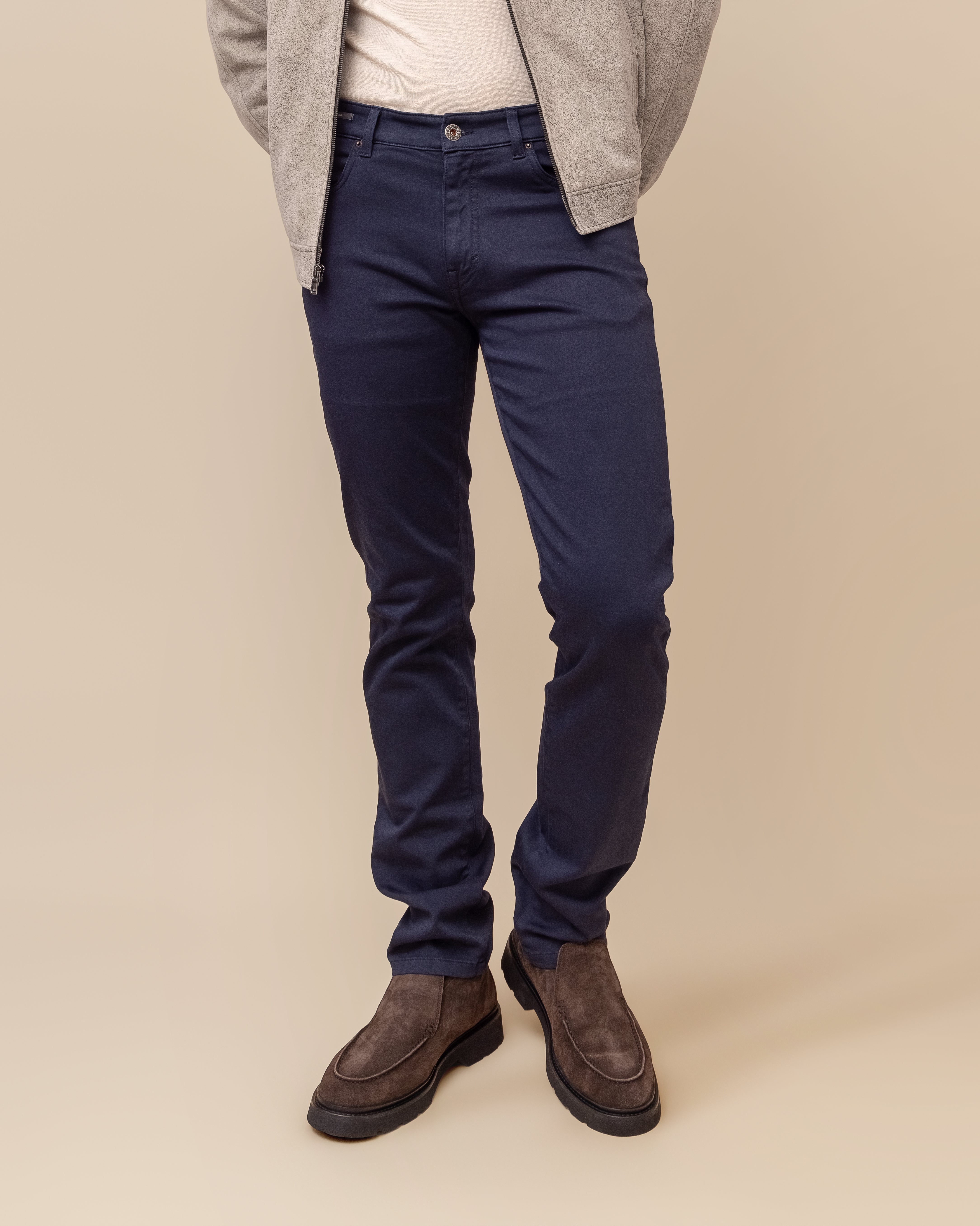 Person wearing navy pants and brown shoes on a beige background