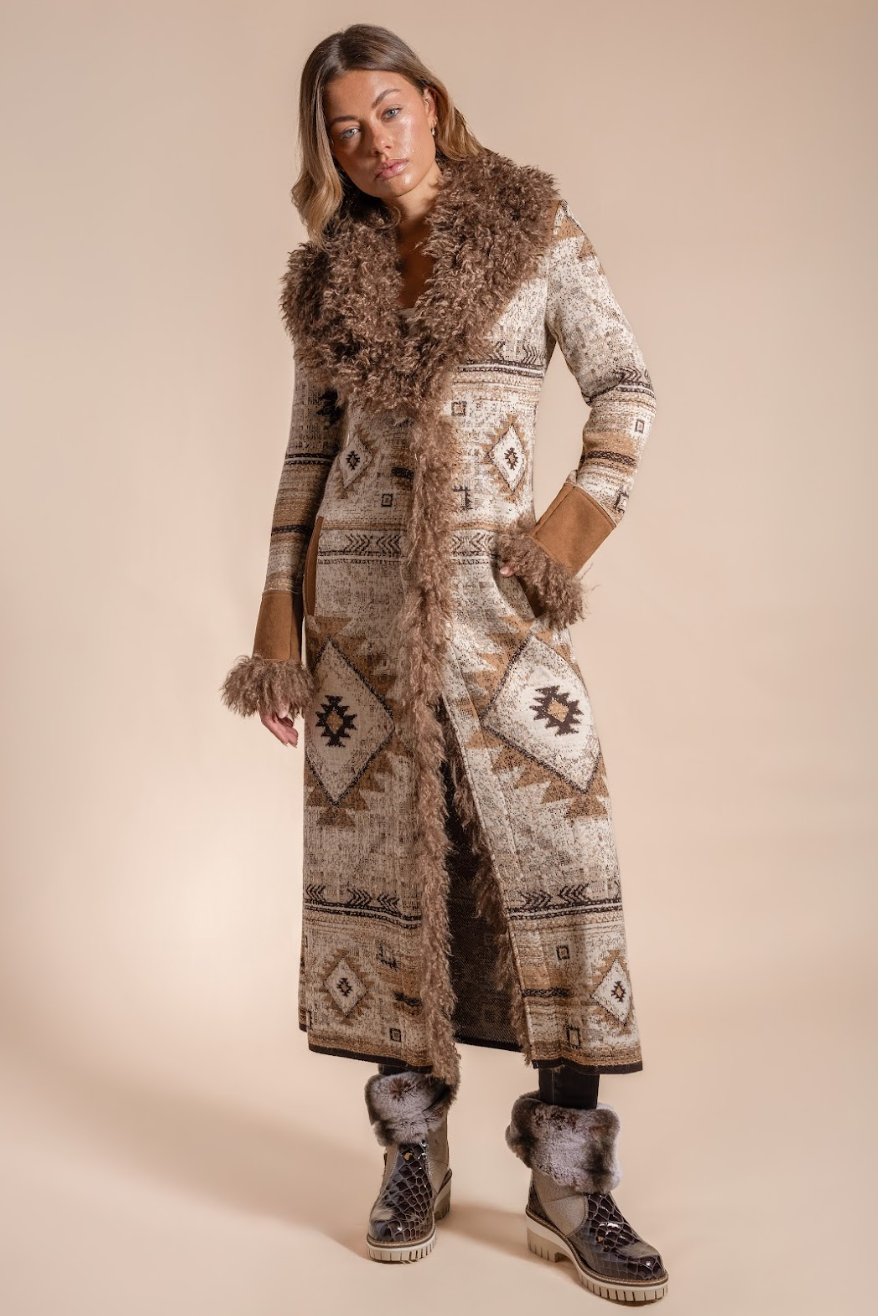 Woman wearing a long patterned coat with fur trim on a beige background