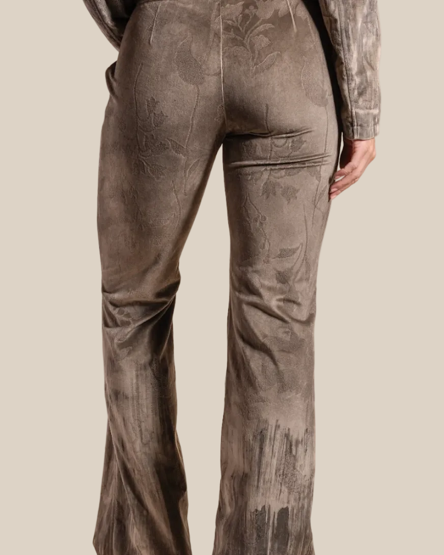 Person wearing washed brown floral pants on a beige background