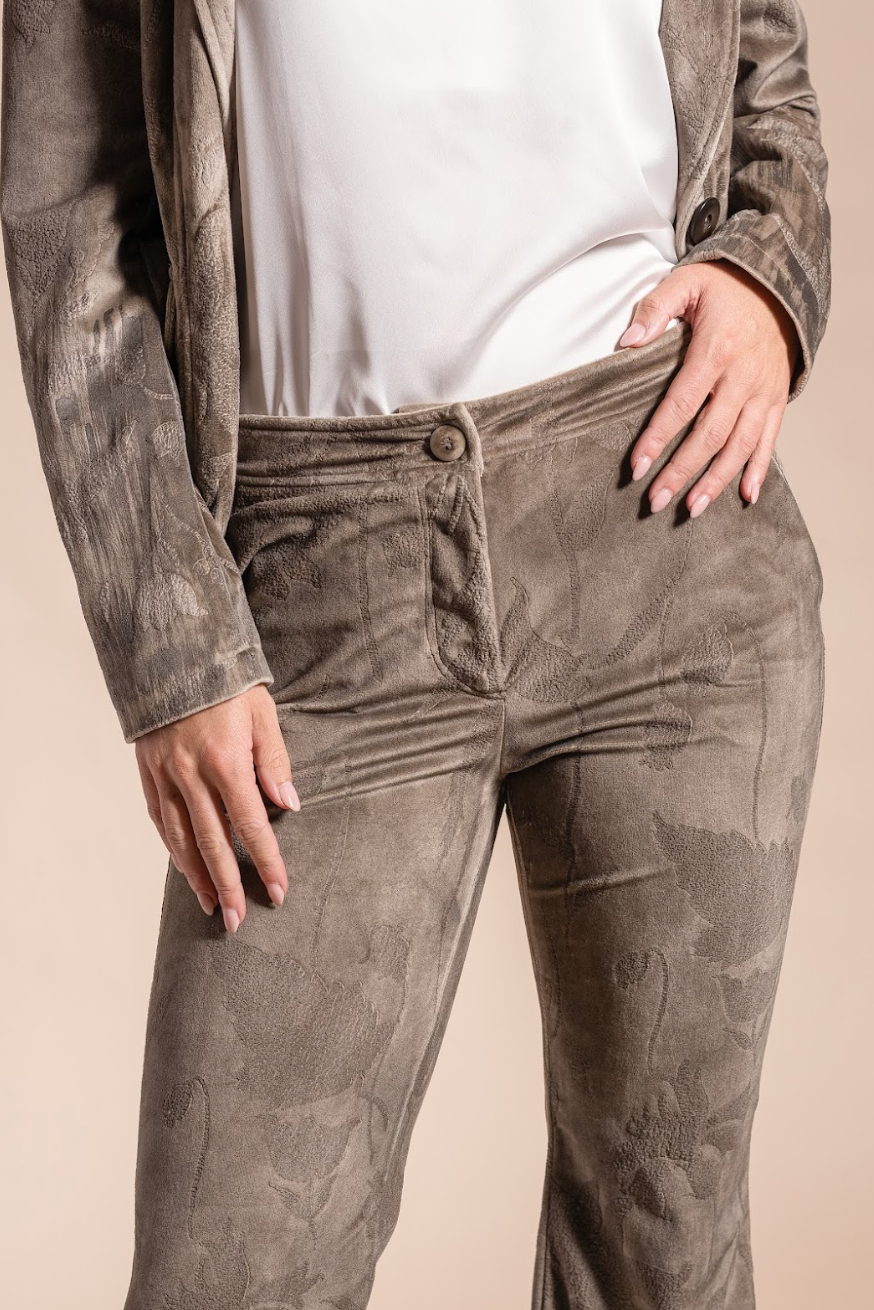 Person wearing brown corduroy pants and a white shirt against a beige background