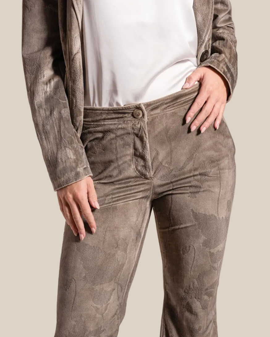 Person wearing brown corduroy pants and a white shirt against a beige background