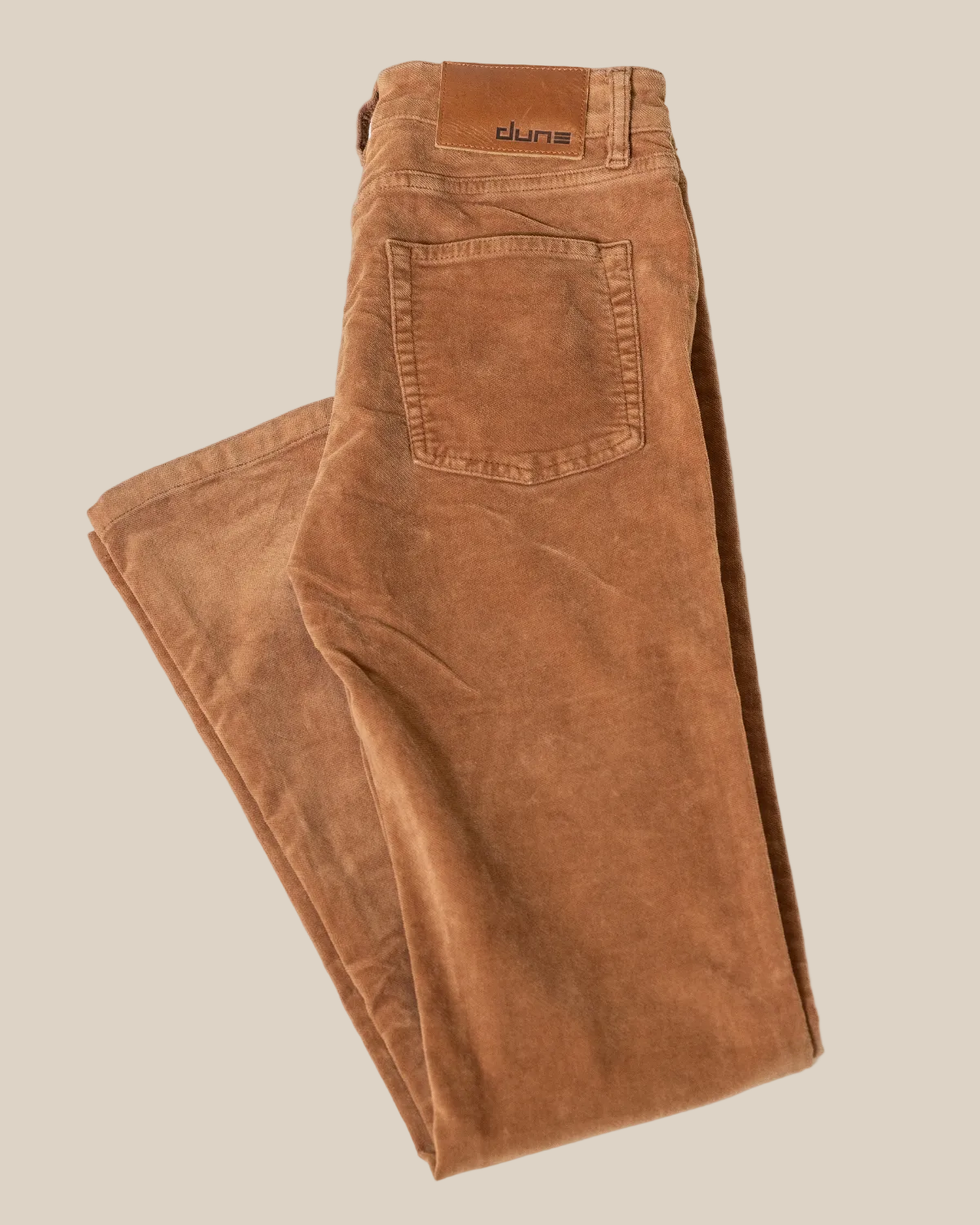 Folded brown jeans on a light gray background
