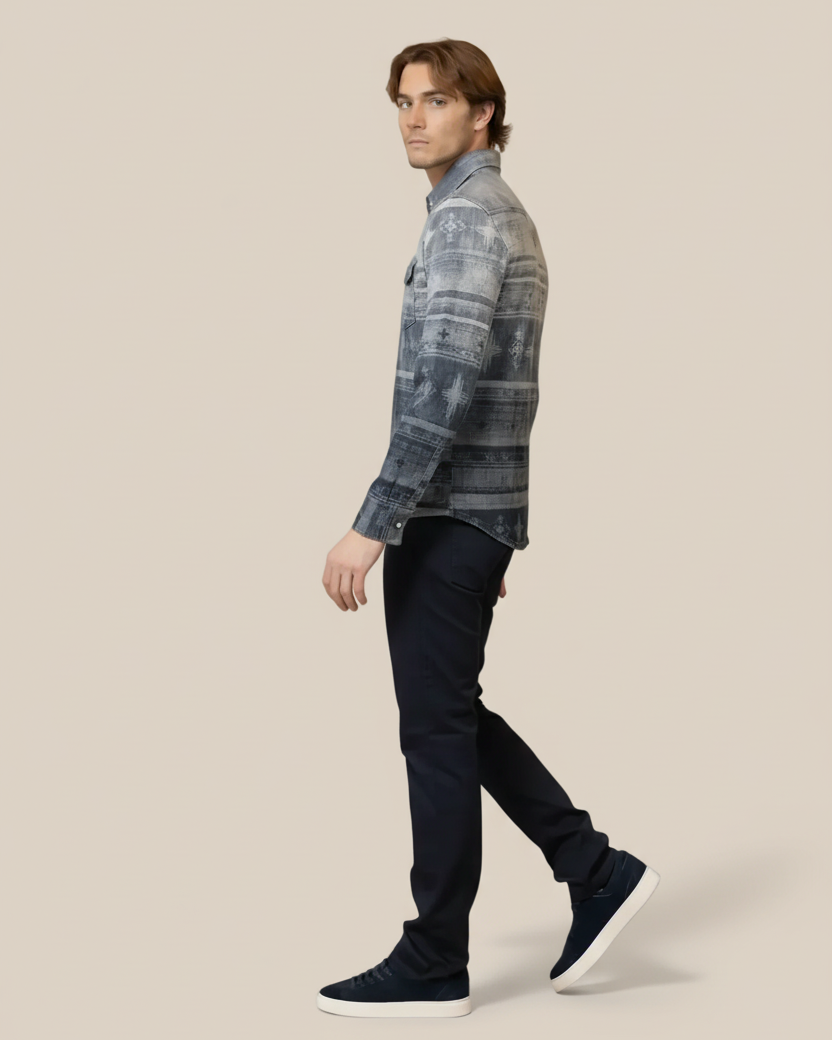 Man wearing a patterned shirt and dark pants on a beige background