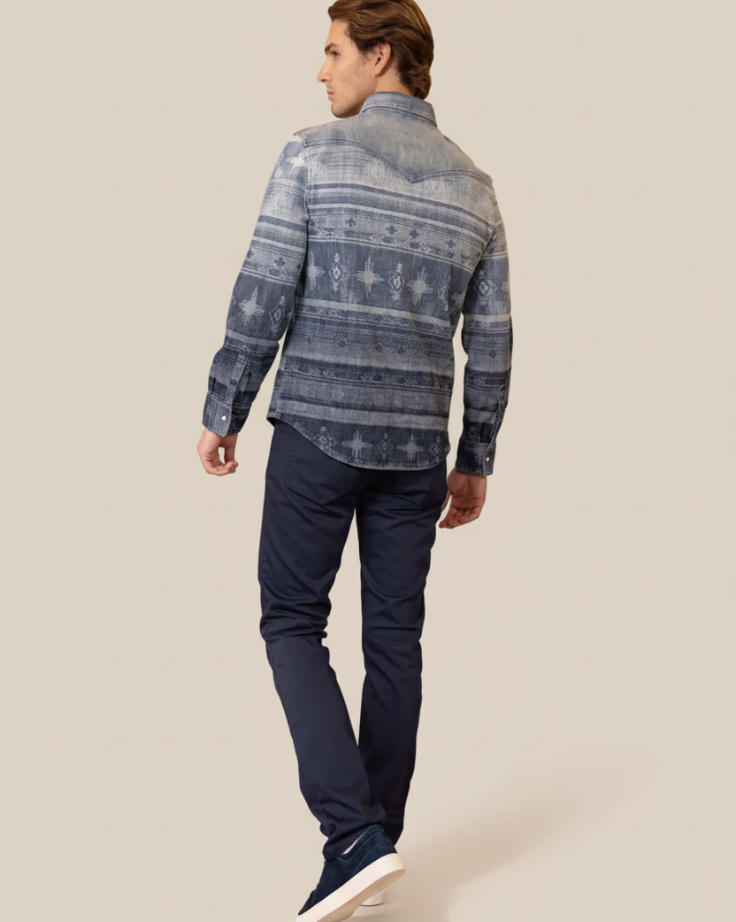 Man wearing a patterned shirt and dark pants on a beige background