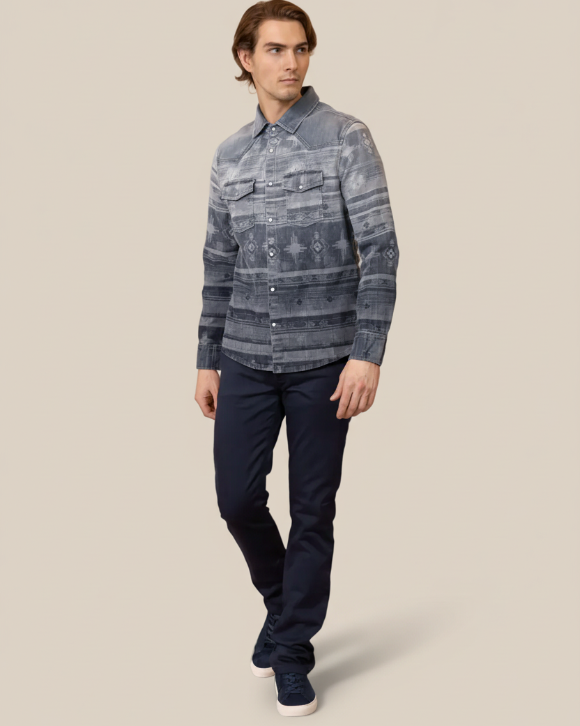 Man wearing a patterned shirt and dark pants on a beige background