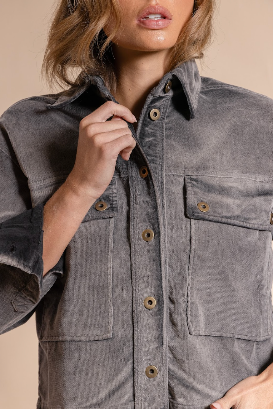 Person wearing a gray jacket with button details on a beige background