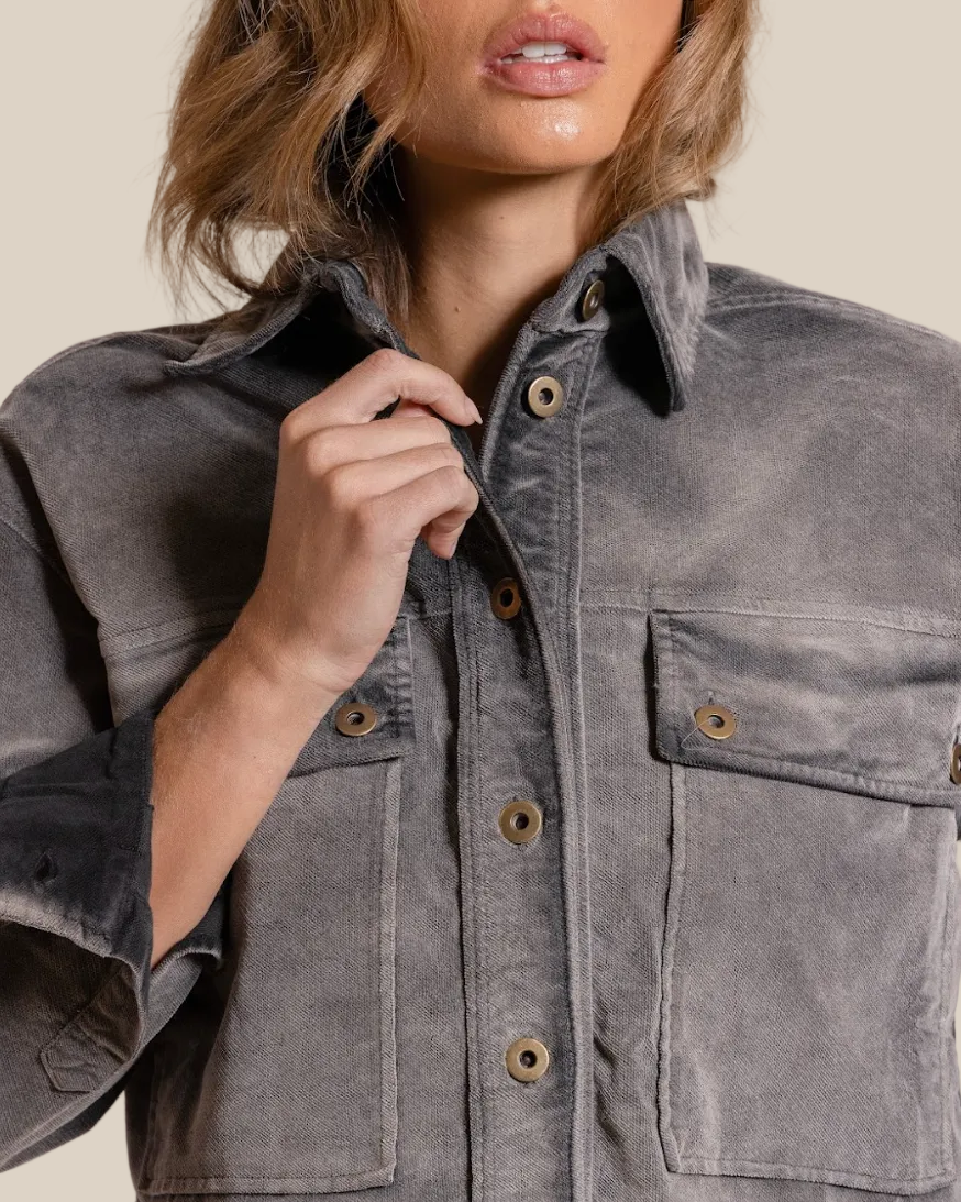 Person wearing a gray jacket with button details on a beige background
