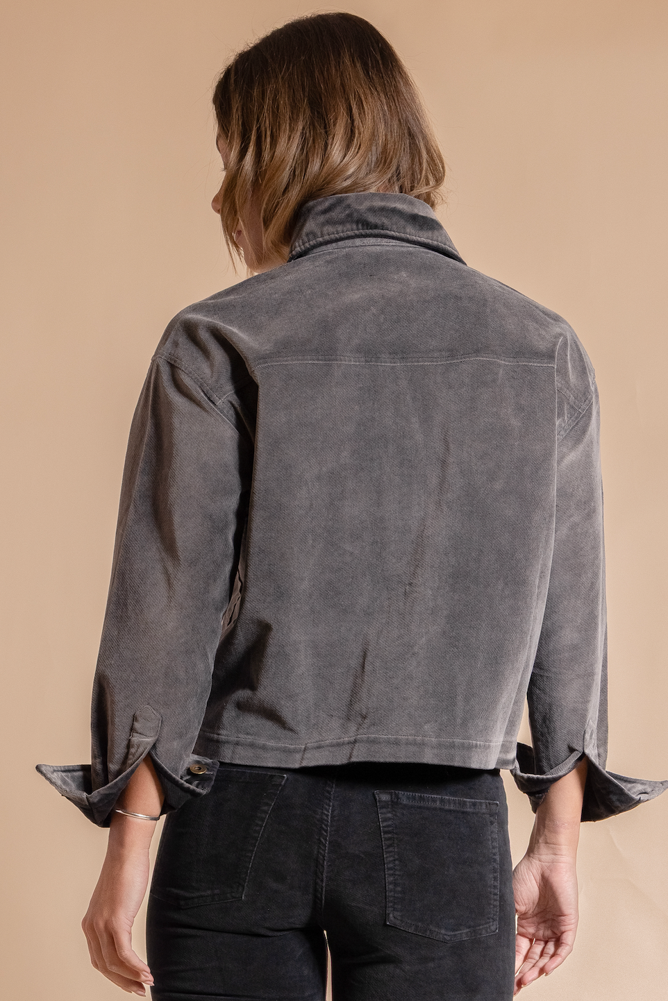 Person wearing a gray jacket on a beige background