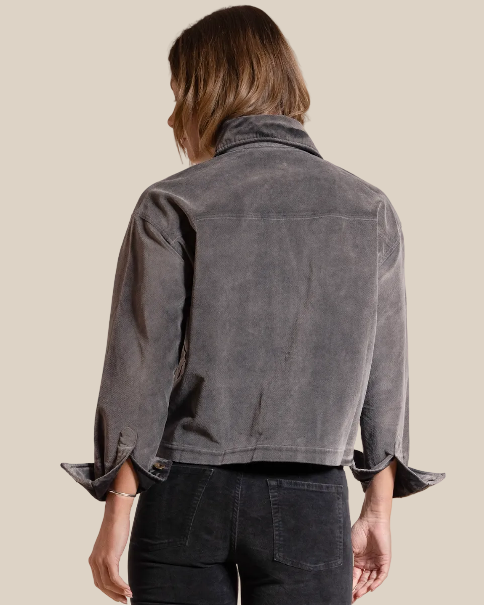 Person wearing a gray jacket on a beige background