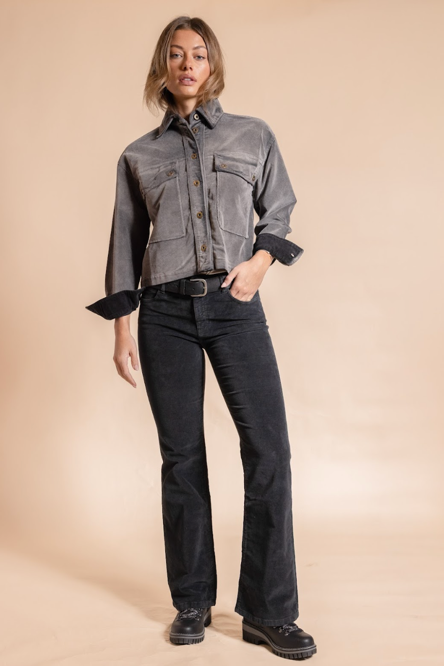 Woman wearing a gray jacket and black pants on a beige background