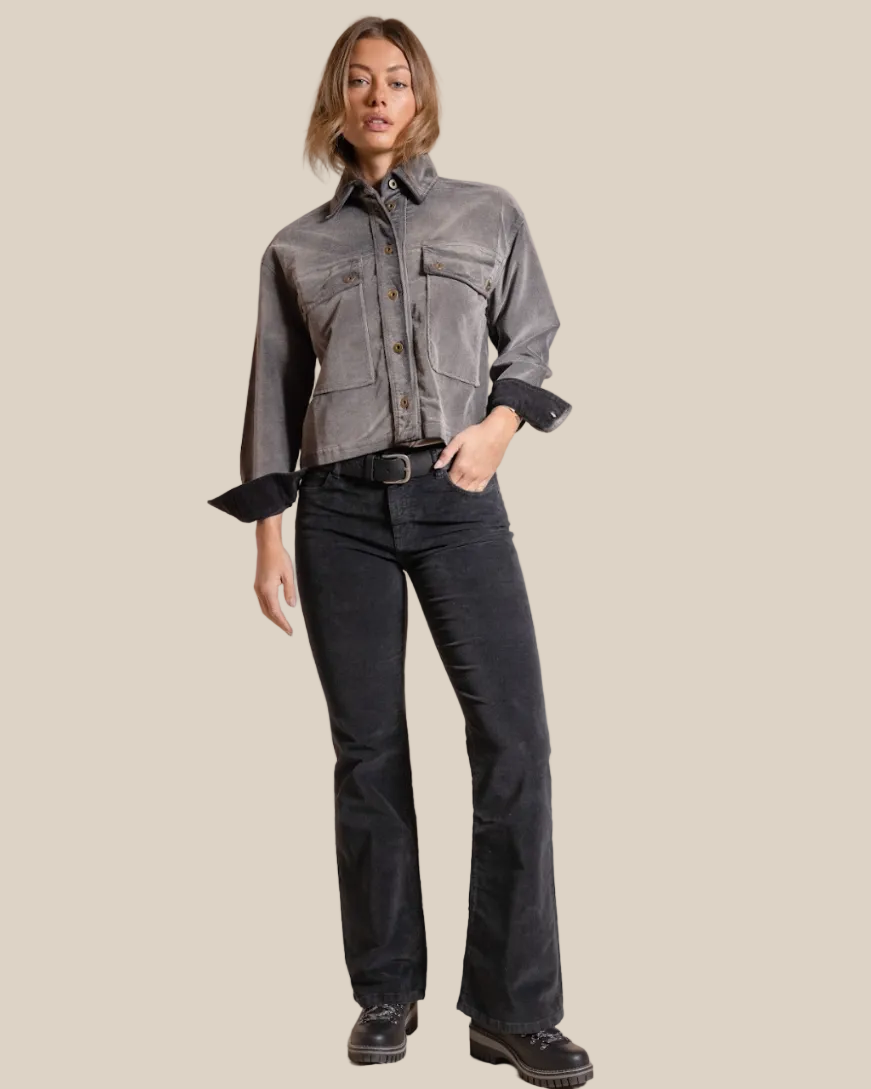 Woman wearing a gray jacket and black pants on a beige background