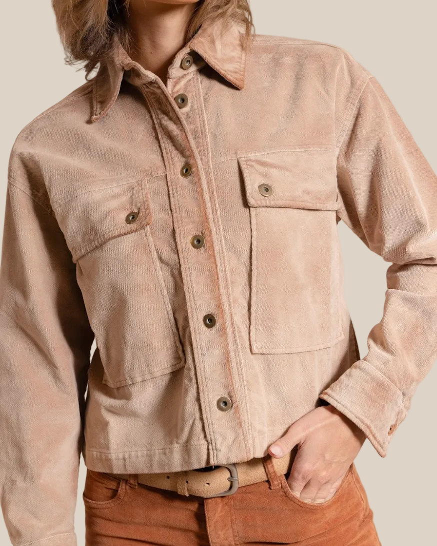 Person wearing a beige jacket and brown pants on a beige background