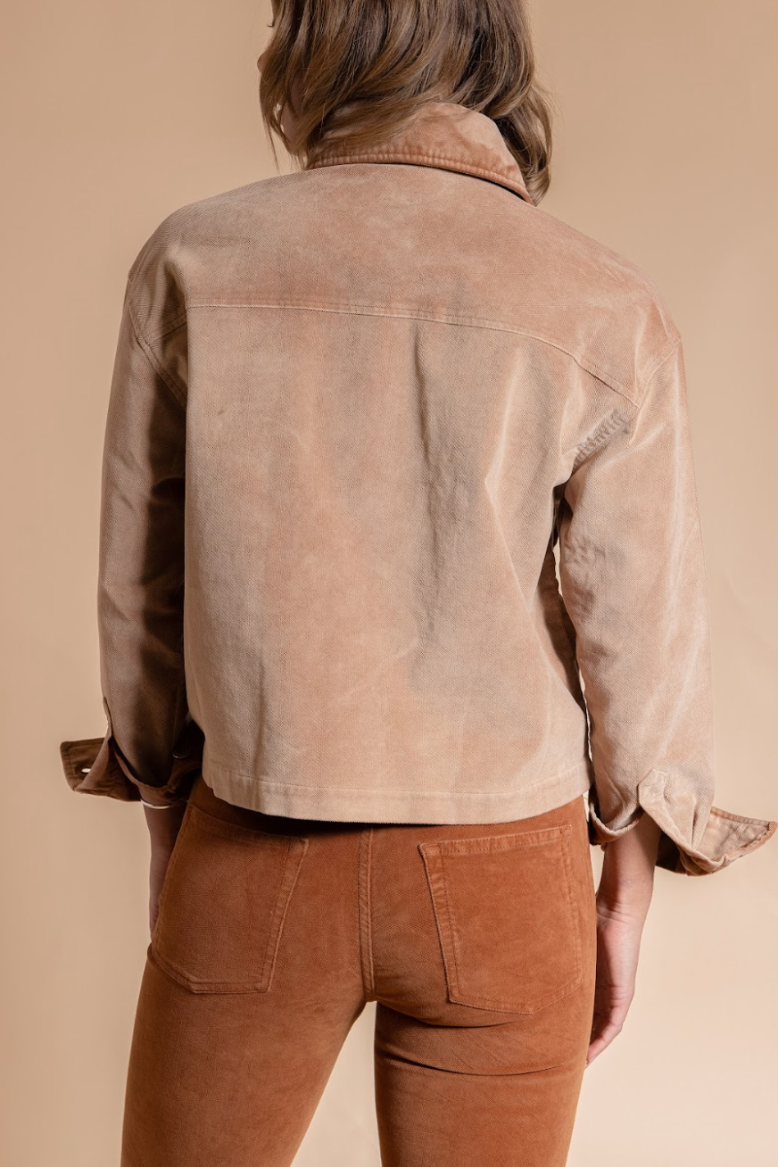 Person wearing a brown jacket and pants against a beige background