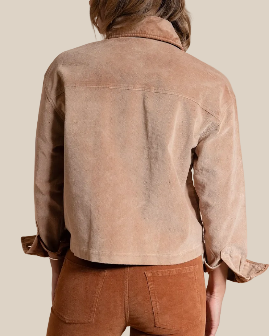 Person wearing a brown jacket and pants against a beige background