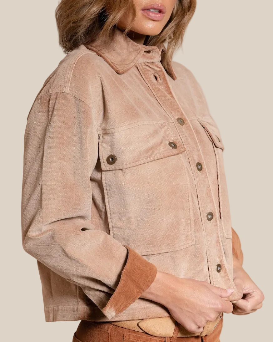 Woman wearing a beige jacket against a beige background