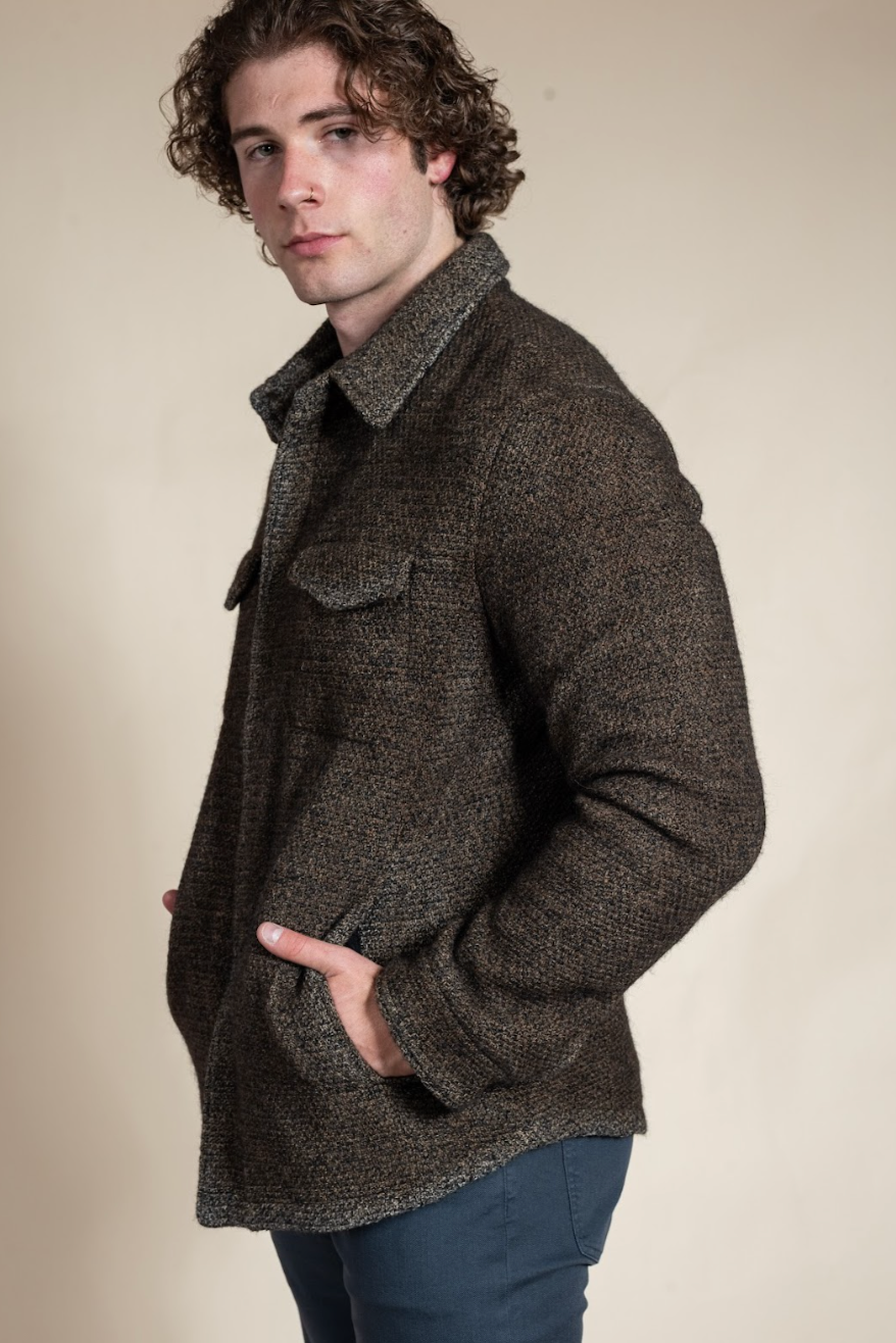 Man wearing a brown textured jacket against a beige background