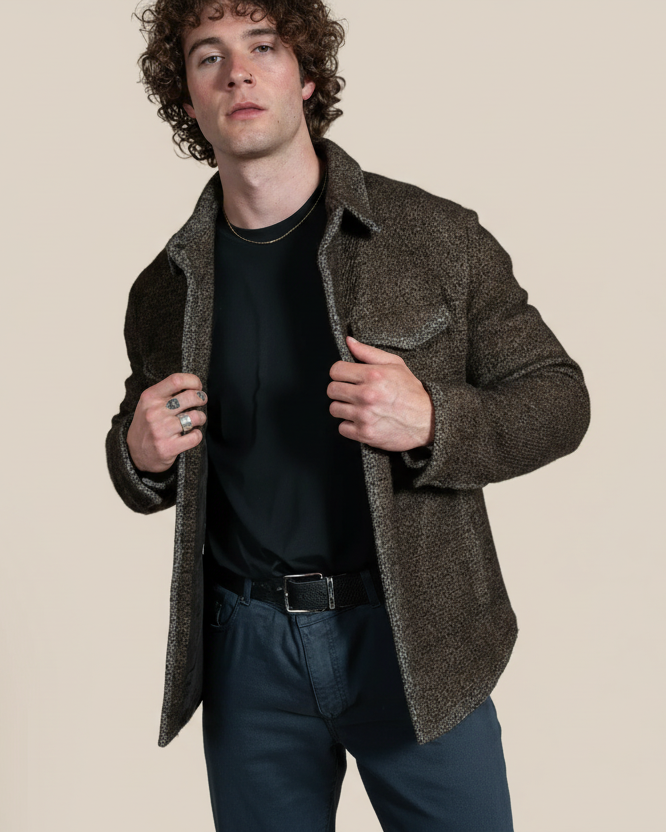 Man wearing a brown coat over a black shirt against a beige background