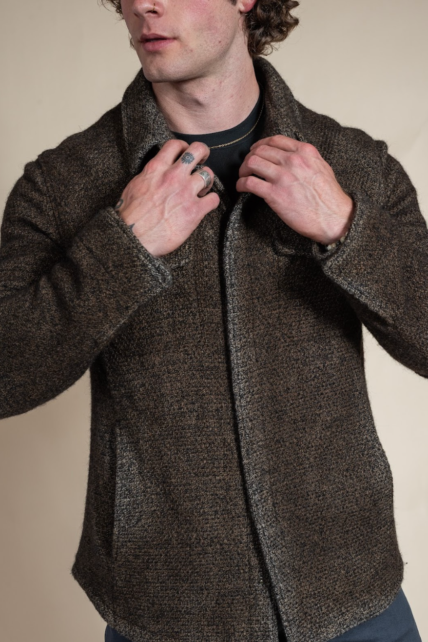 Man wearing a brown textured jacket against a beige background