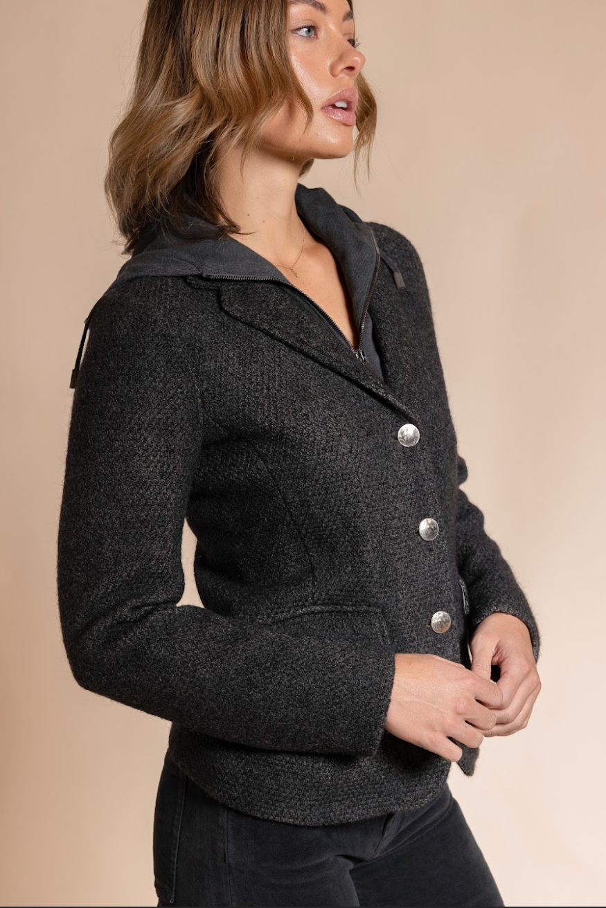 Woman wearing a dark gray peacoat with silver buttons on a beige background