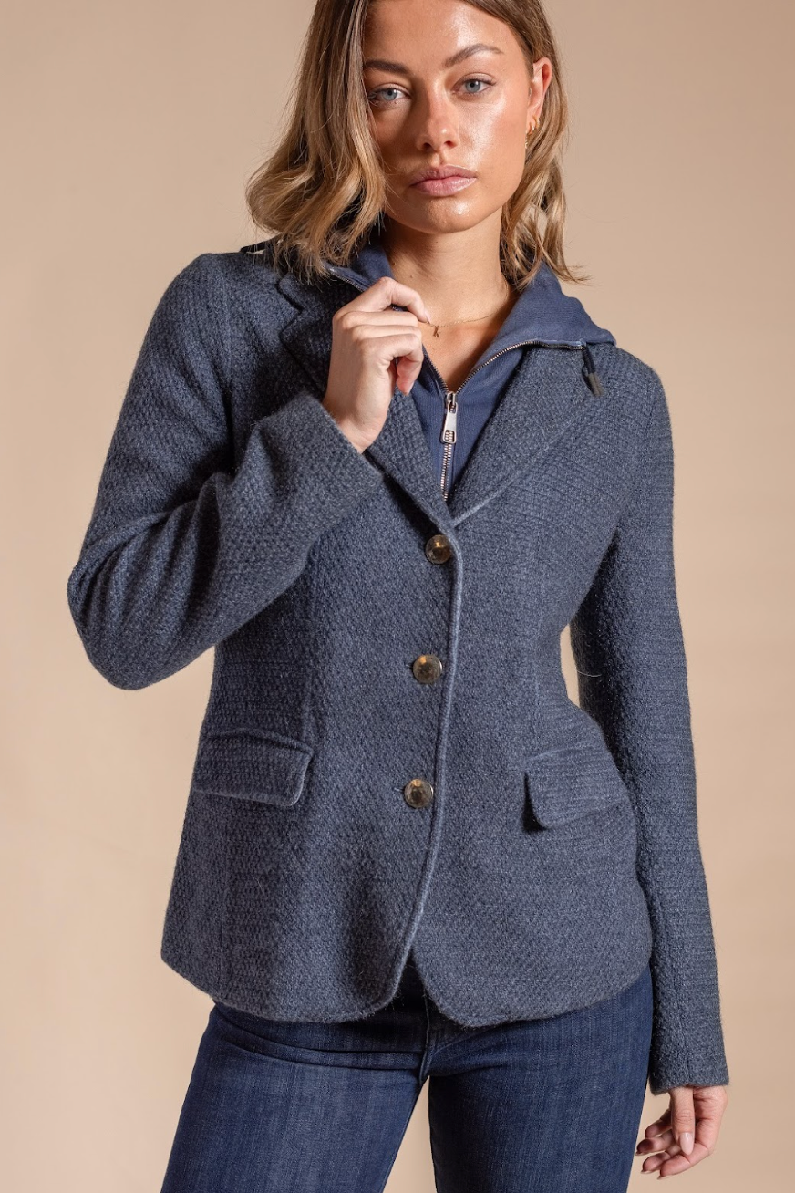 Woman wearing a blue textured blazer against a beige background