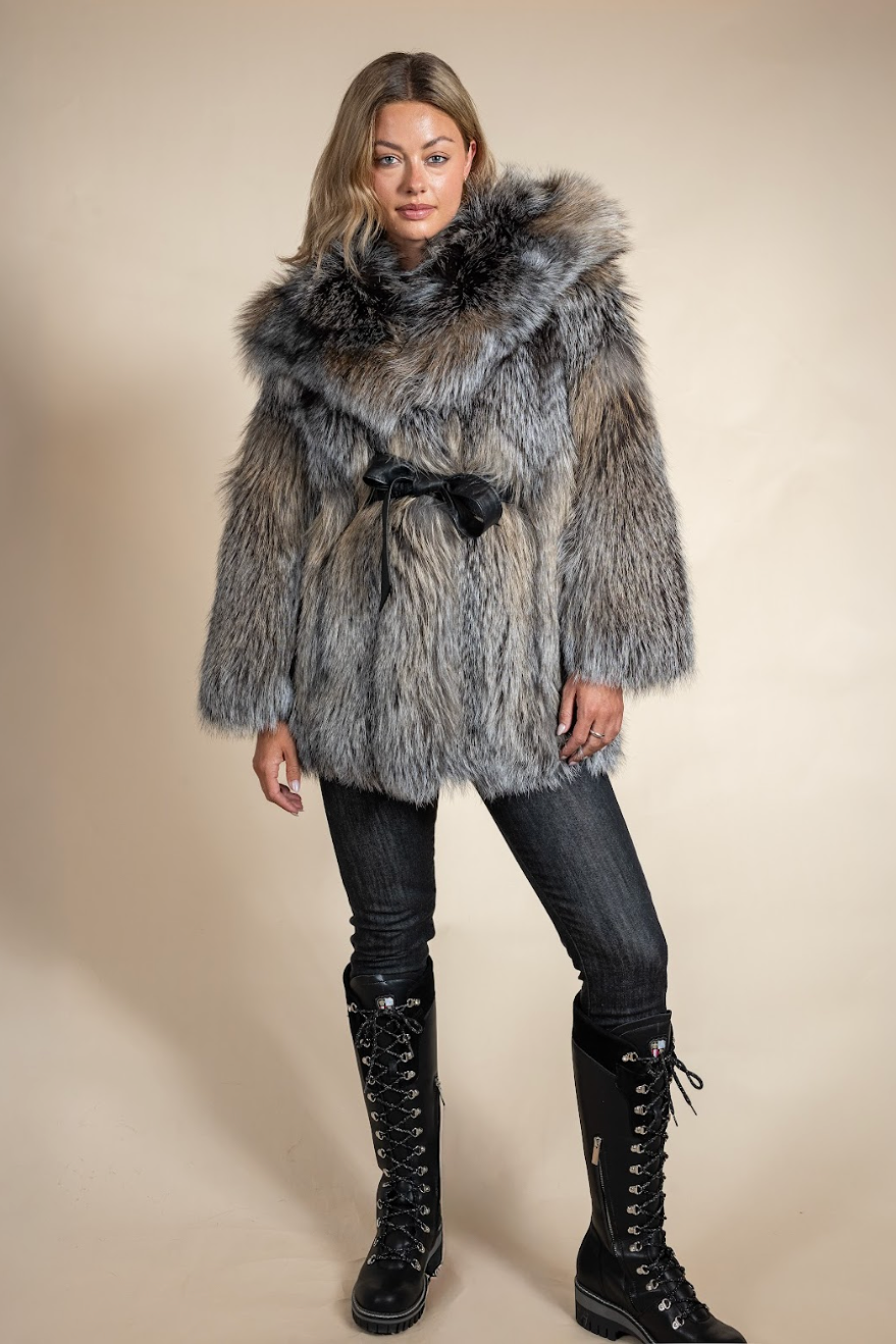 Woman wearing a fur coat with a hood against a beige background