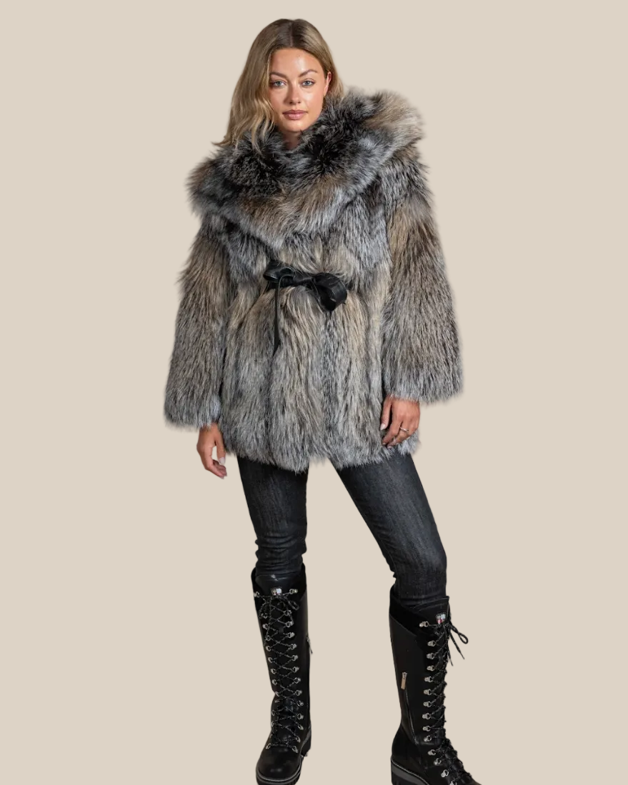 Woman wearing a fur coat with a hood against a beige background