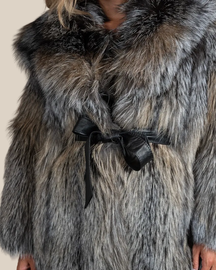 Close-up of a fur coat with a black bow on a beige background