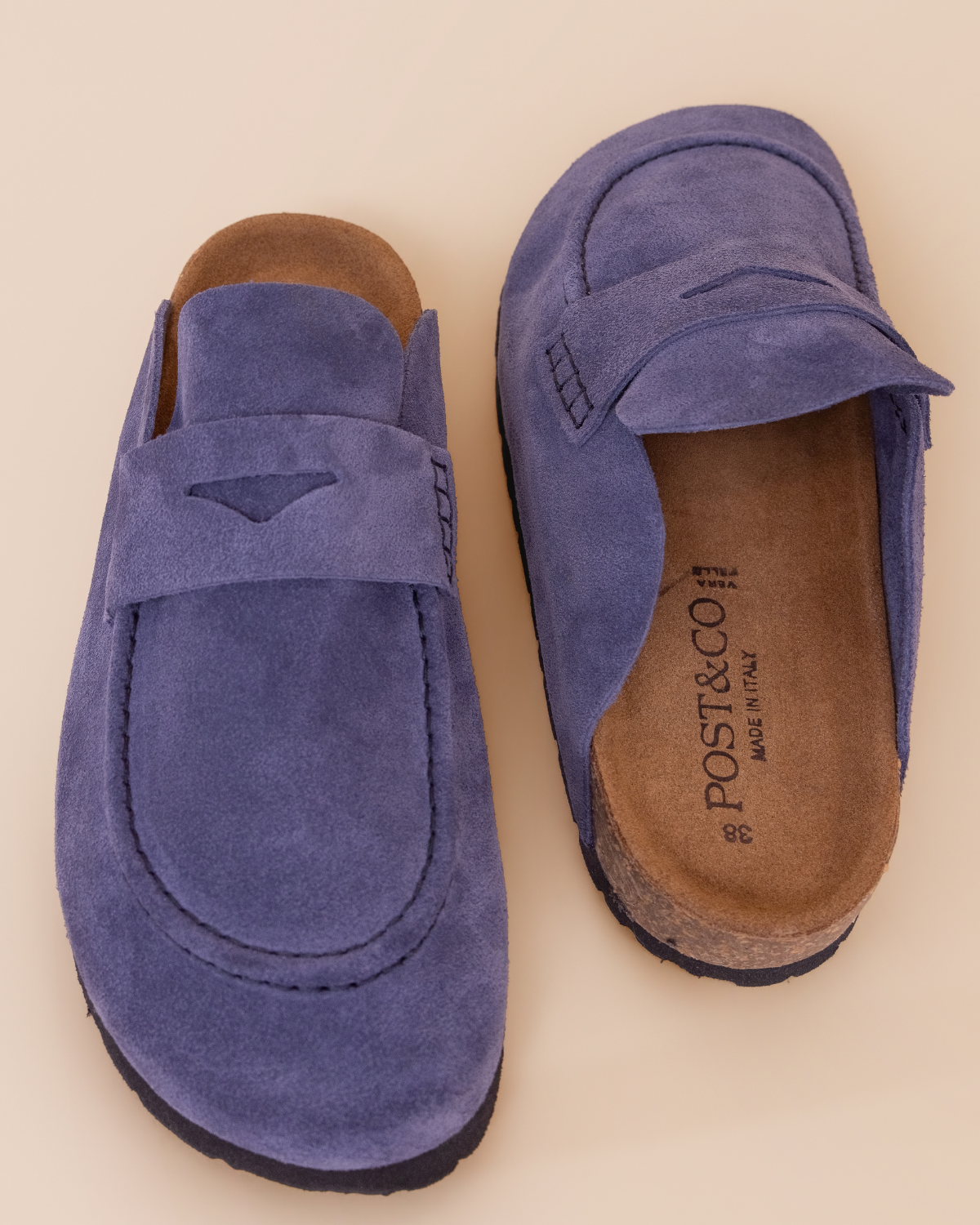 Pair of blue suede slippers with brown soles on a beige background