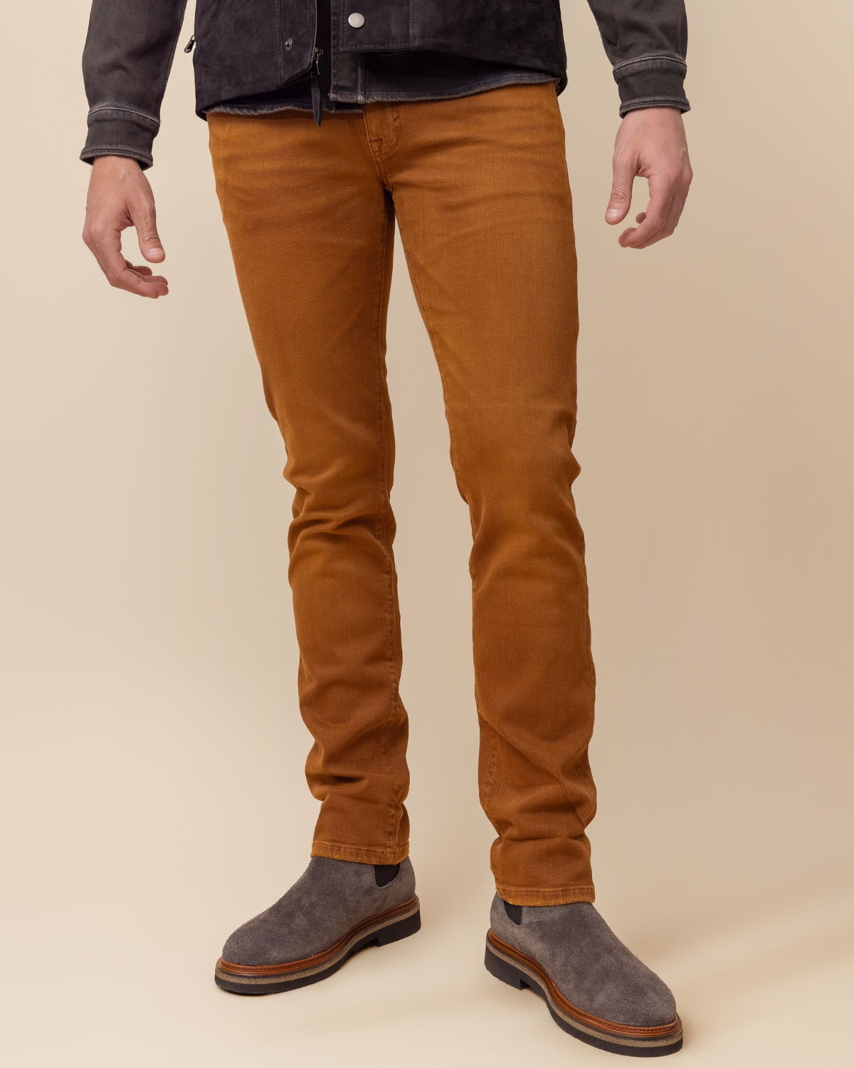 Person wearing brown pants and dark shoes on a beige background