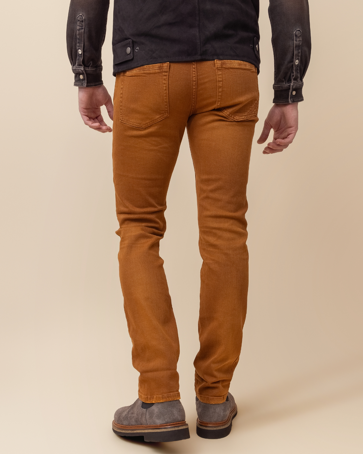 Person wearing brown pants and gray boots on a beige background
