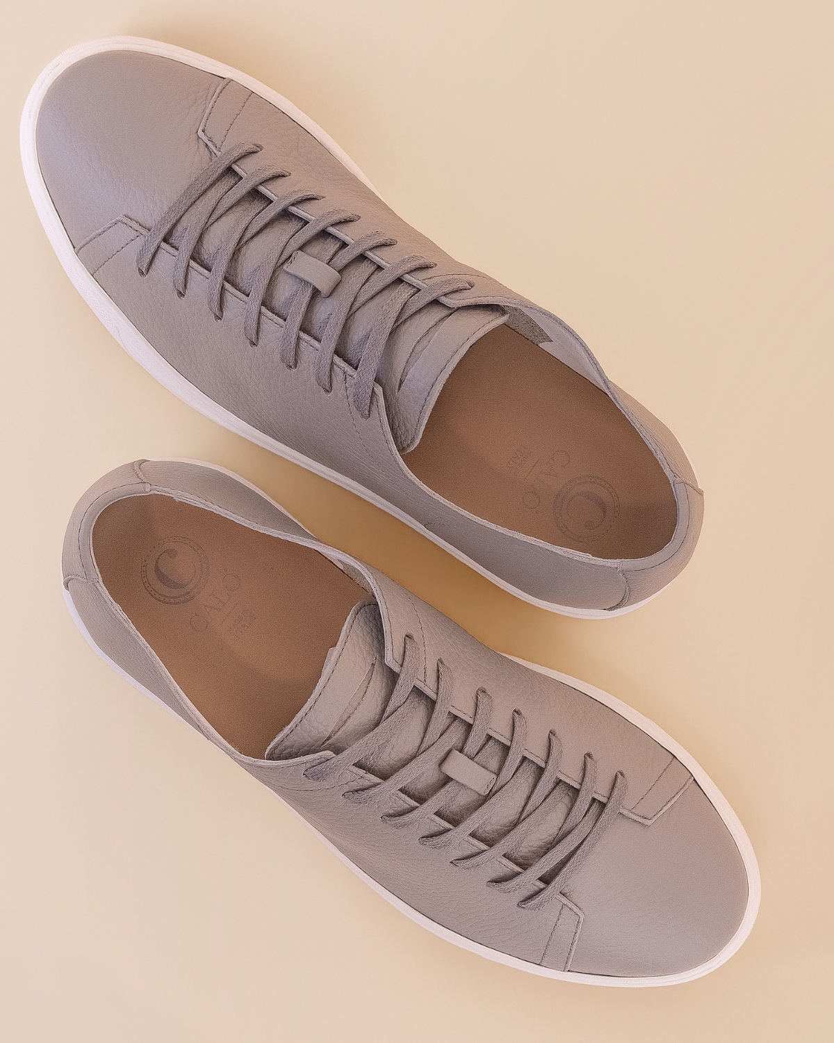 Pair of light gray sneakers on a beige background