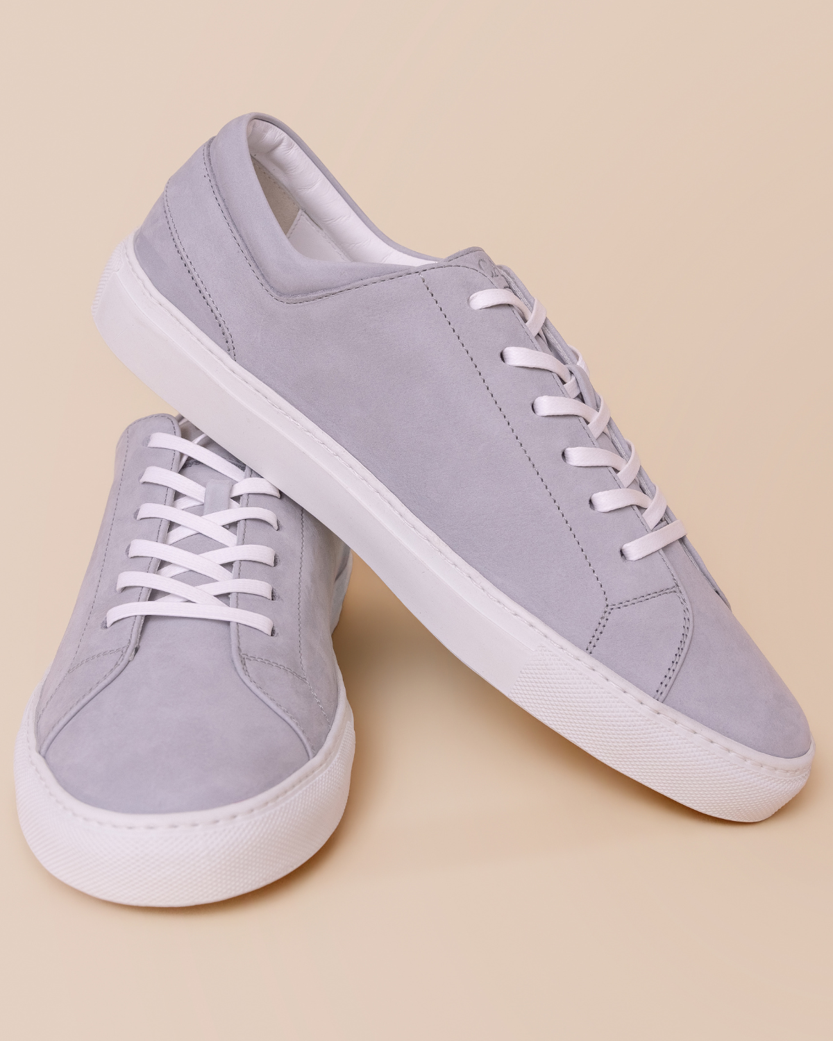 Pair of light purple sneakers with white laces on a beige background