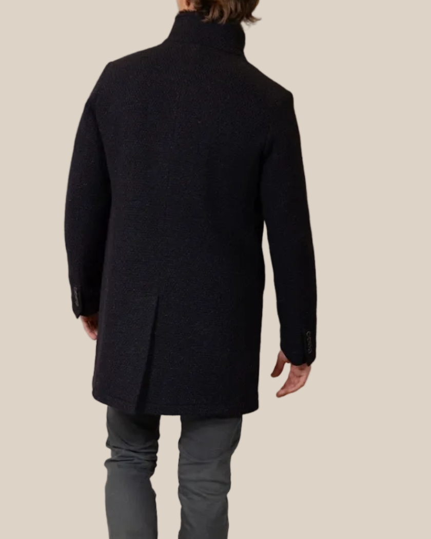 Man wearing a black coat and gray jeans on a beige background