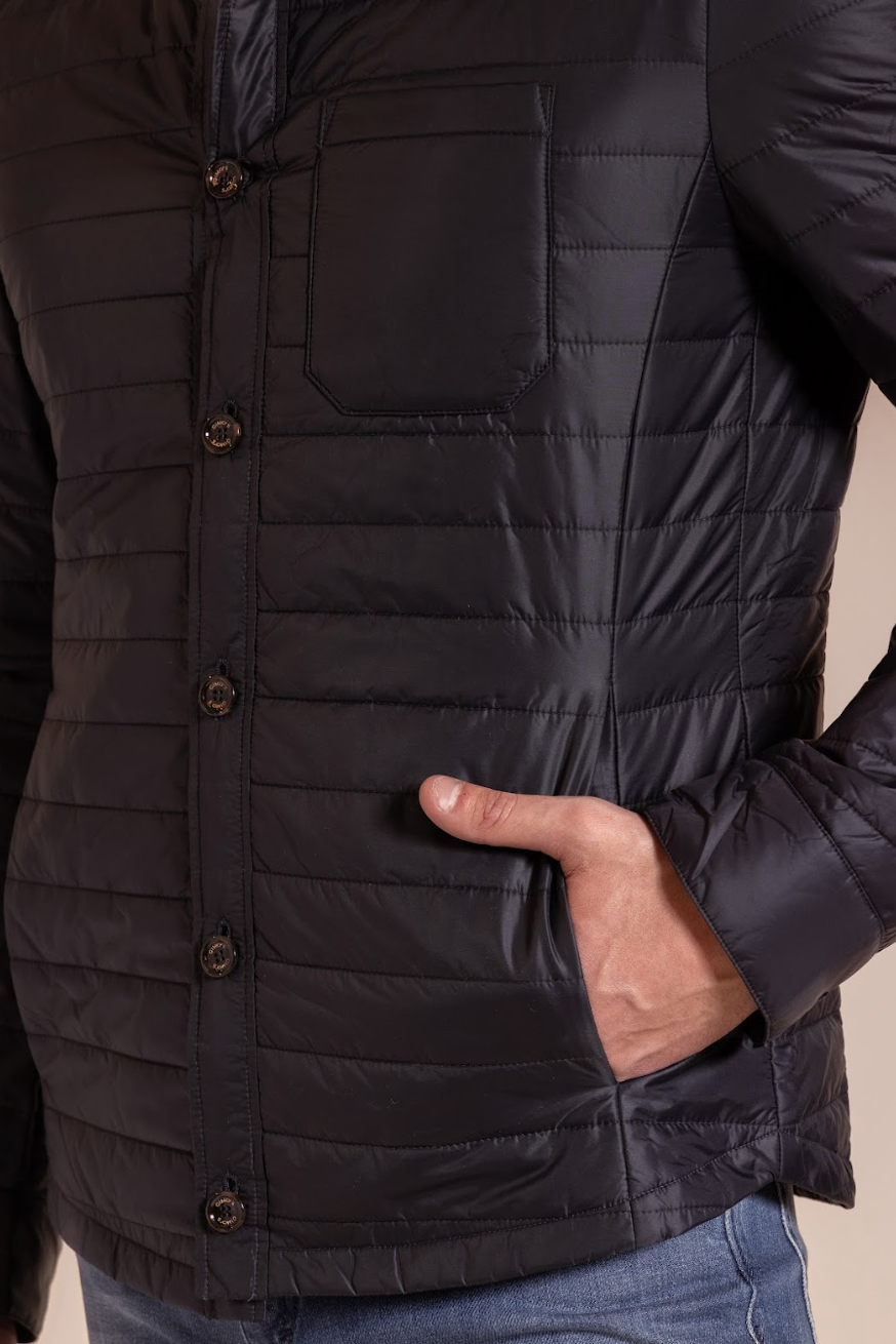 Close-up of a person wearing a black quilted jacket with a neutral background
