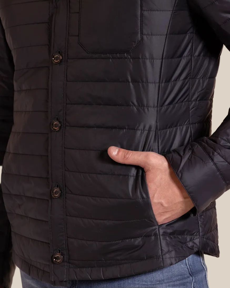 Close-up of a person wearing a black quilted jacket with a neutral background