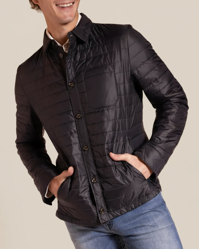 Man wearing a black quilted jacket with a beige background