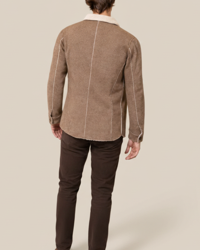 Person wearing a brown jacket with a white collar on a white background