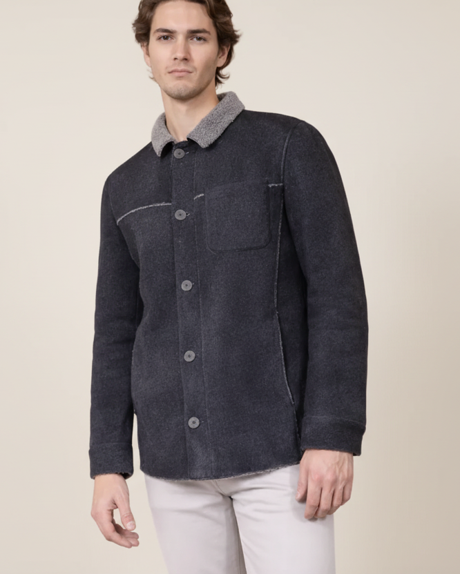 Man wearing a dark denim jacket with a light gray collar on a beige background