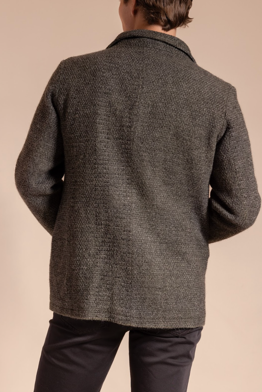 Person wearing a textured gray coat on a beige background