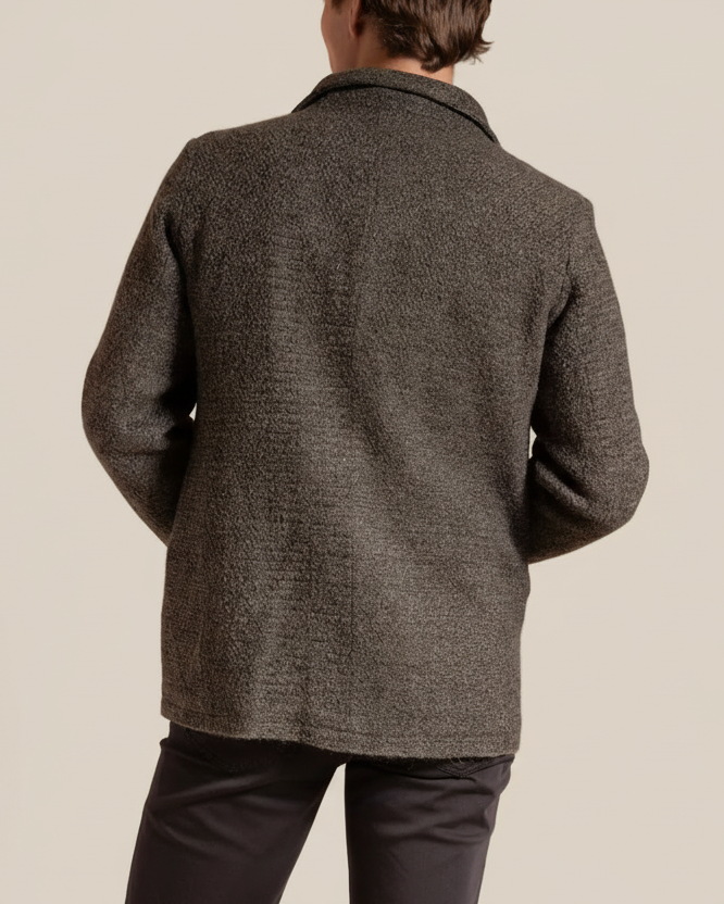 Person wearing a textured gray coat on a beige background