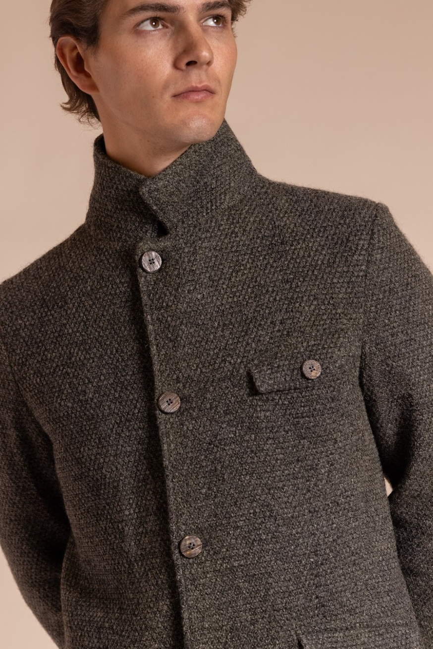 Man wearing a dark brown textured jacket against a beige background