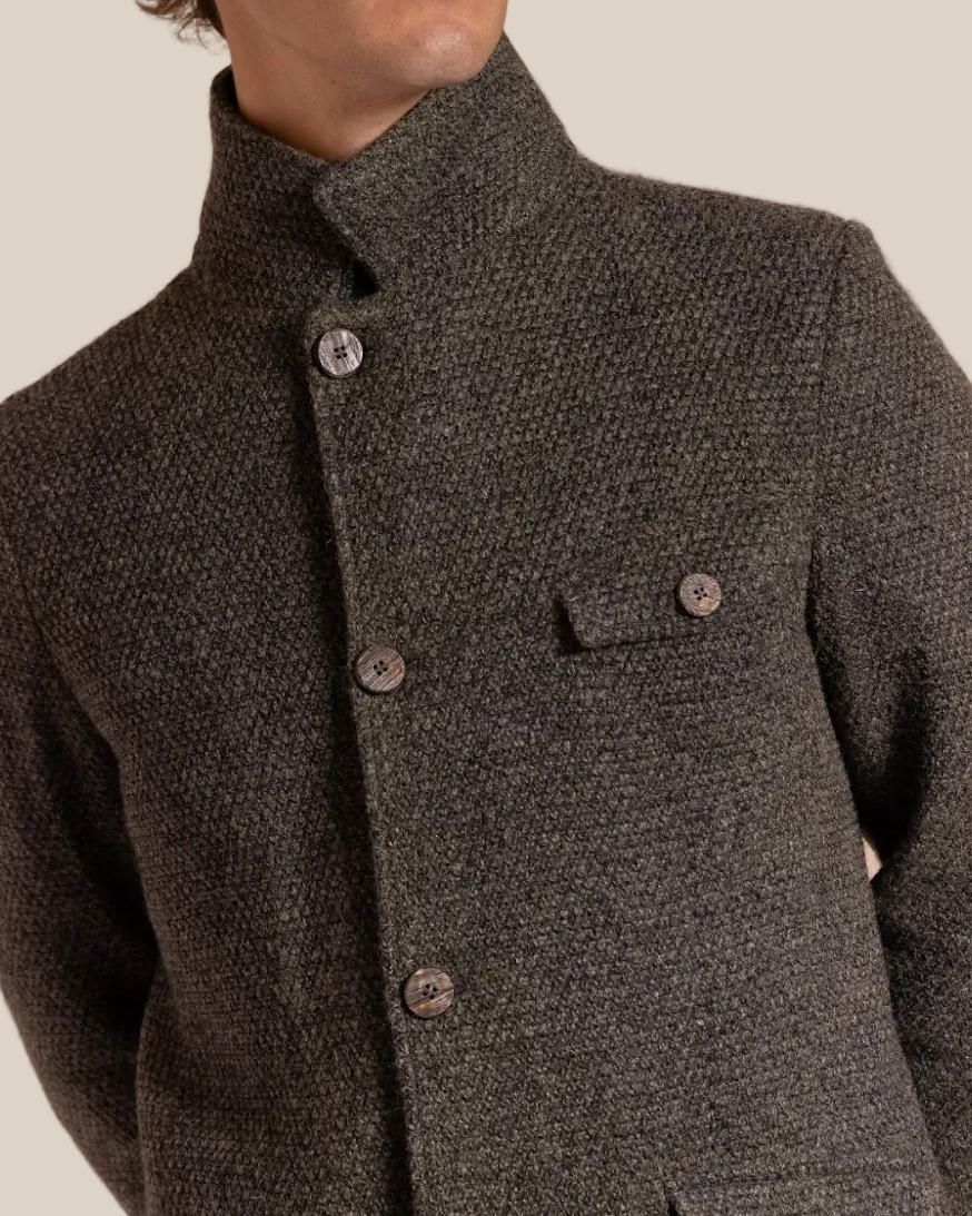 Man wearing a dark brown textured jacket against a beige background