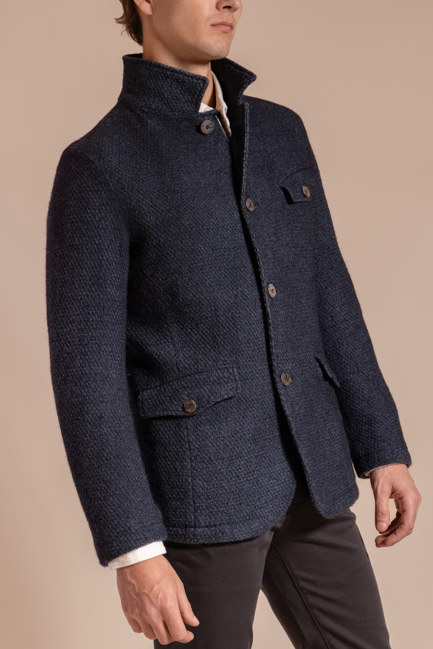 Man wearing a navy blue textured jacket on a beige background