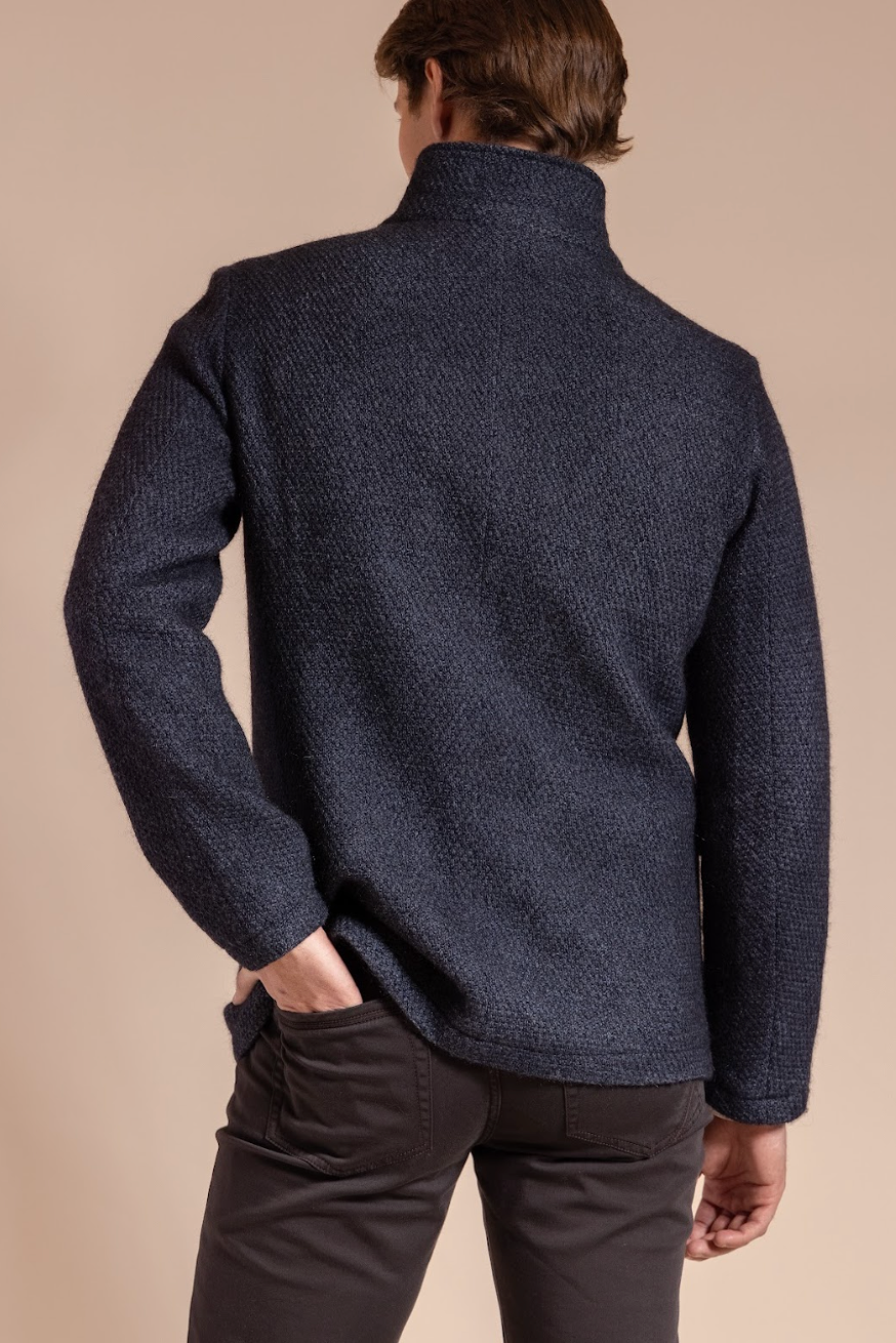 Man wearing a dark blue textured jacket on a beige background