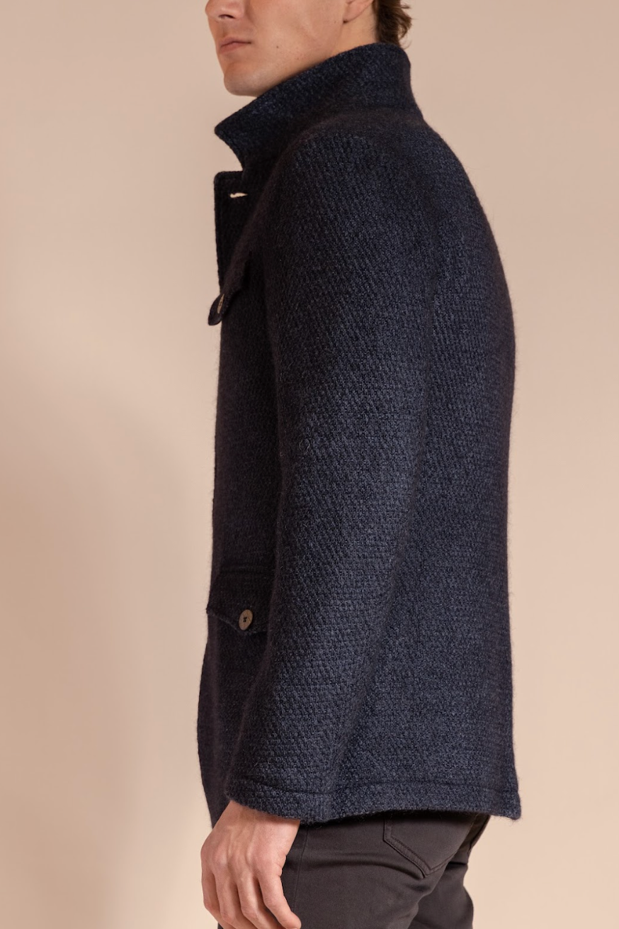 Man wearing a dark blue textured coat on a beige background