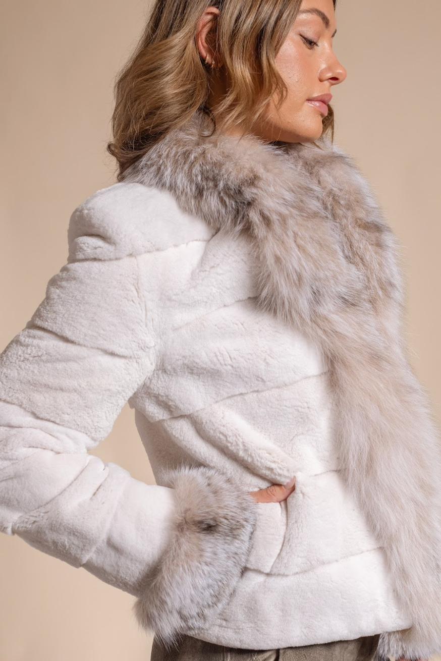 Woman wearing a white fur coat with a fur-lined hood against a beige background