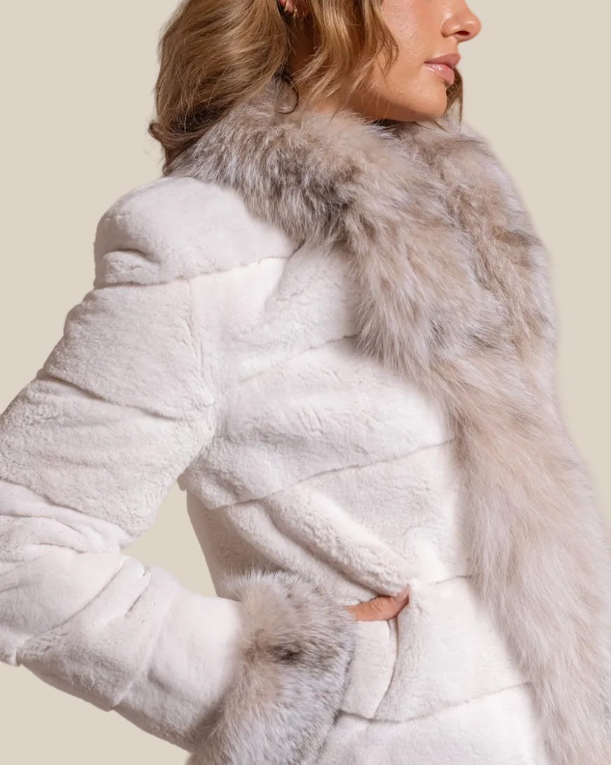 Woman wearing a white fur coat with a fur-lined hood against a beige background