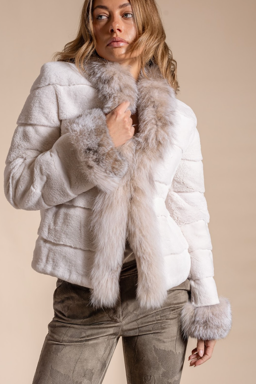 Woman wearing a white fur jacket with gray fur trim on a beige background