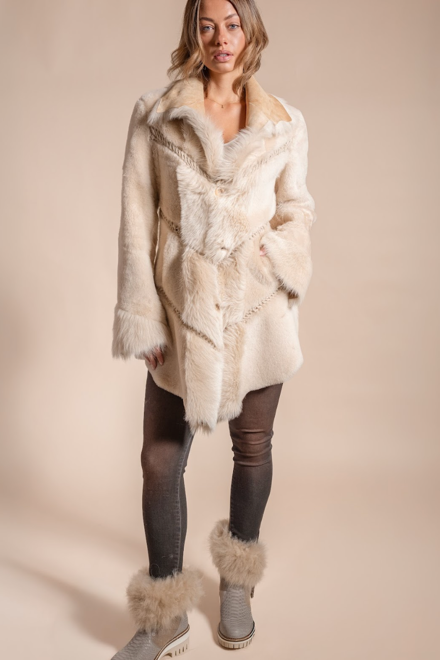 Woman wearing a cream fur coat with matching fur boots on a beige background
